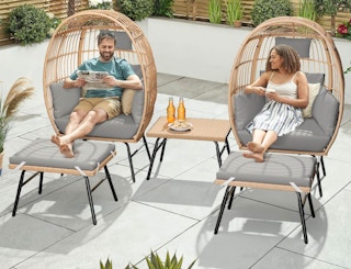 two people sitting in egg-shaped chairs outside