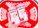 hand holding 2 nature's bounty hair, skin, nails gummies over a target basket