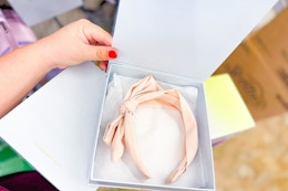 hand holding a box with a kristin ess headband in it