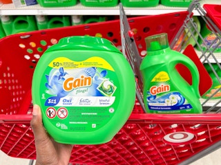 holding up Gain flings in front of shopping cart at Target