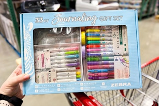 person holding a journaling gift set on a cart