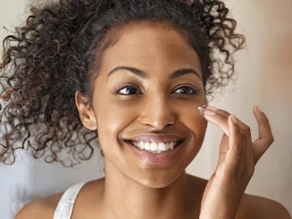woman applying moisturizer to face
