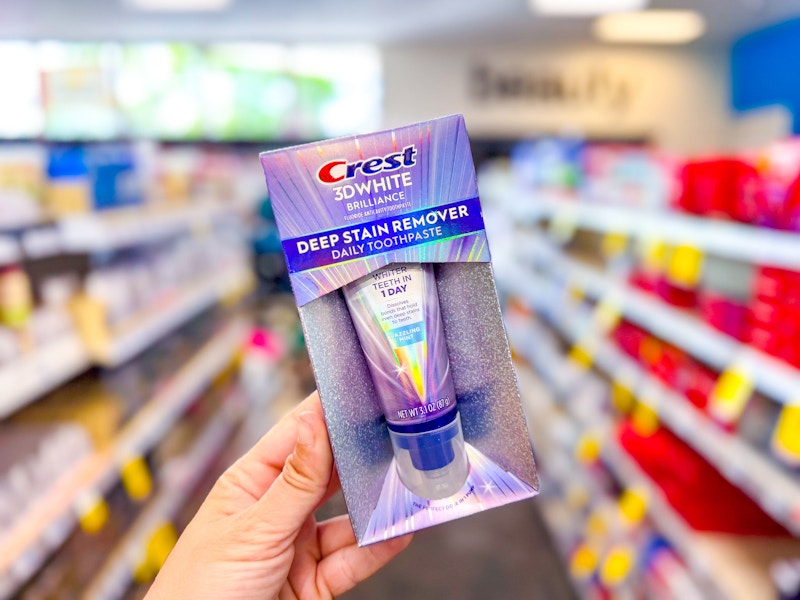 person holding crest 3d white deep stain remover toothpaste in an aisle