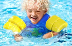 a kid swimming in a swim vest in a pool