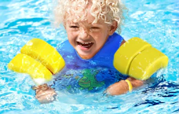 a kid swimming in a swim vest in a pool