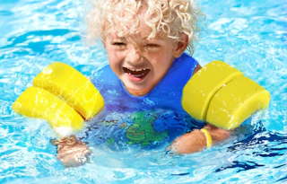 a kid swimming in a swim vest in a pool
