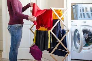 A person hanging clothes to dry on racks.