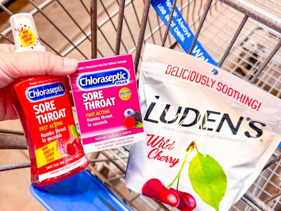 hand holding chloraseptic throat spray and lozenges with ludens drops in walmart cart