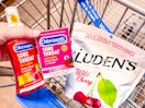hand holding chloraseptic throat spray and lozenges with ludens drops in walmart cart