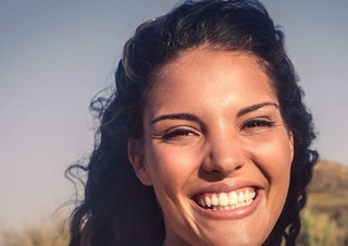 A woman wearing ChapStick while smiling.