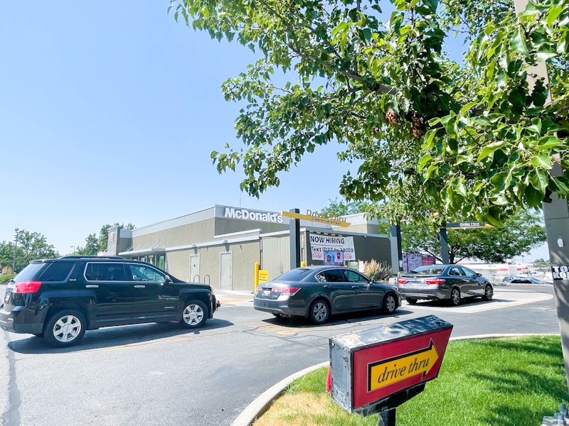 A line of cars going through the McDonald's Drive Thru during the day.