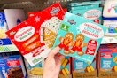 hand holding dollar tree gingerbread house kit and christmas cookie kit