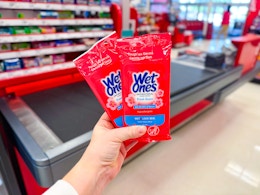 hand holding wet ones wipes in front of a checkout lane