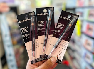 hand holding three packs of Covergirl eye pencils