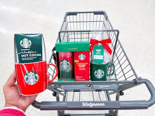 hand holding Starbucks mug gift set in front of shopping cart with more Starbucks gift sets