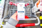 person holding eucerin night cream moisturizer over a cart