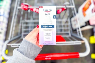 person holding eucerin night cream moisturizer over a cart
