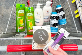 person holding covergirl setting powder and mascara over a cart with garnier shampoo, dove hand wash, and gillette foamy shave cream in it