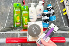 person holding covergirl setting powder and mascara over a cart with garnier shampoo, dove hand wash, and gillette foamy shave cream in it