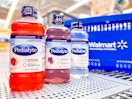 three bottles of pedialyte electrolyte solution on walmart shelf next to hand cart