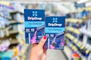 person holding 2 packs of drip drop hydration powder in an aisle