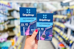 person holding 2 packs of drip drop hydration powder in an aisle
