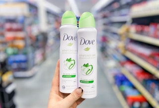 hand holding two bottles of dove cool essentials dry spray deodorant in a store aisle