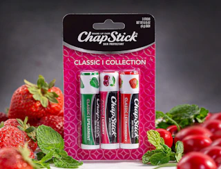 a 3-pack of Chapstick next to cherries and strawberries