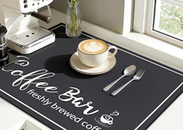 a latte in a cup on a mat next to an espresso machine 