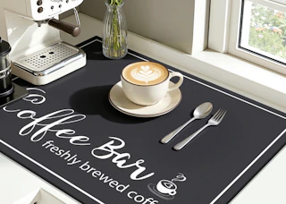 a latte in a cup on a mat next to an espresso machine