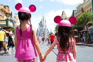 Two children wearing mickey mouse ears holding hands at Disney World