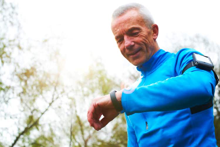 Older man in exercise clothes wearing a fitness tracker and arm band phone holder 
