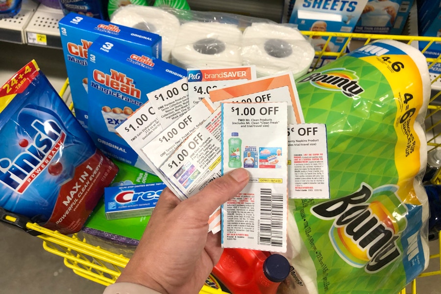 A person holding a stack of coupons next to products inside Dollar General