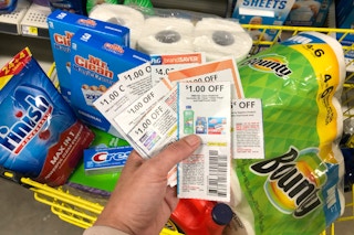 A person holding a stack of coupons next to products inside Dollar General