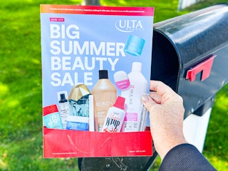 someone taking the ulta big summer beauty sale mailer out of their mailbox