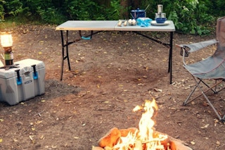 lifestyle image of a folding table set up at a campfire
