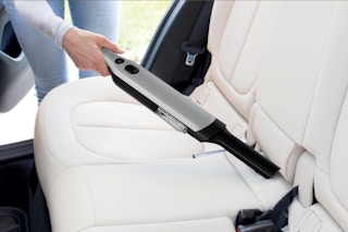 Woman using the Shark WANDVAC Cordless Hand Vacuum.