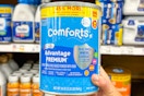 hand holding a can of comforts baby formula