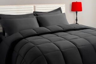 A dark grey 7-piece comforter set on a bed