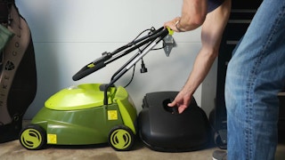 stock photo of sunjoe lawn mower being put away in garage