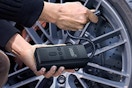 AIRSURE Tire Inflator Portable Air Compressor being used by a guy on his car tire.