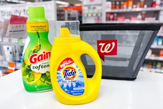 bottle of detergent and fabric softener in front of walgreens shopping basket on store counter