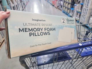 hand holding a box of two memory foam pillows in a cart