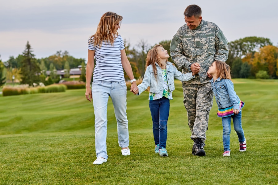 Person in Uniform with family while walking on a large yard