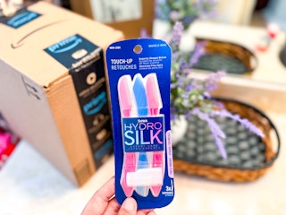 Schick Hydro Silk Touch-Up Dermaplaning Tool held up next to an amazon box