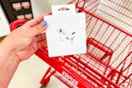hand holding Airpod Pro headphones next to a staples shopping cart