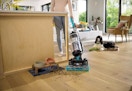 woman using a bissell swivel pet vacuum to suck up dog food