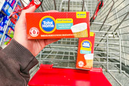 person holding a box of trash bags over a cart