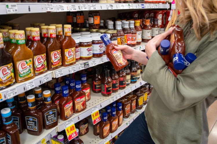 Person holding bbq bottles in a grocery store