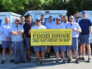 USPS employees holding a large banner for the Stamp Out Hunger day